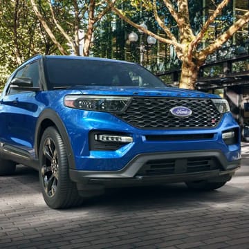 Blue Ford Explorer parked on a brick paved street.