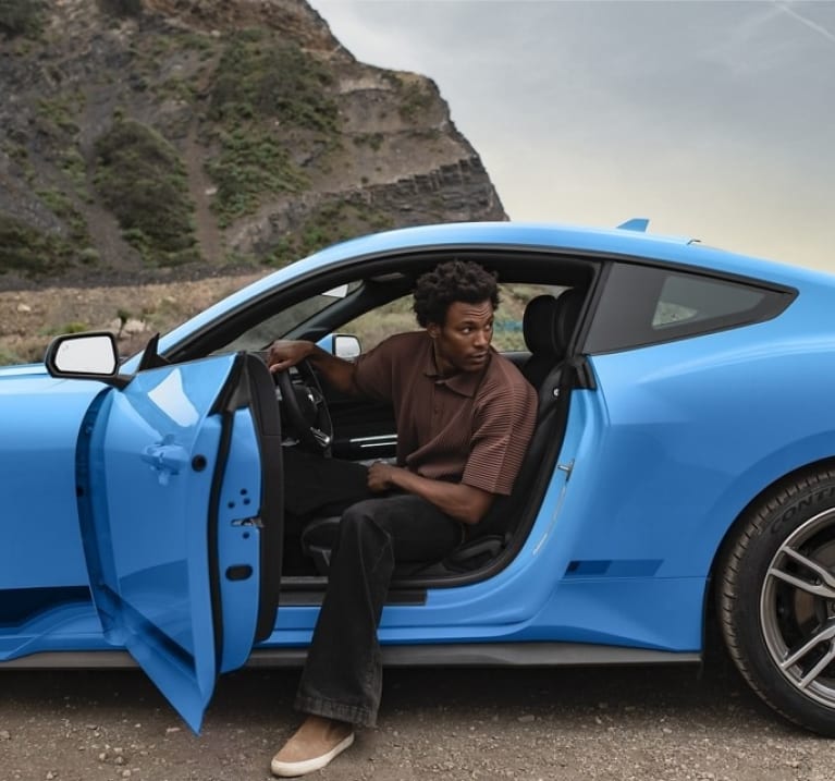 driver stepping out of a Grabber Blue Mustang