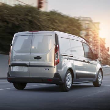 A white Ford Transit Connect Cargo Van driving away.