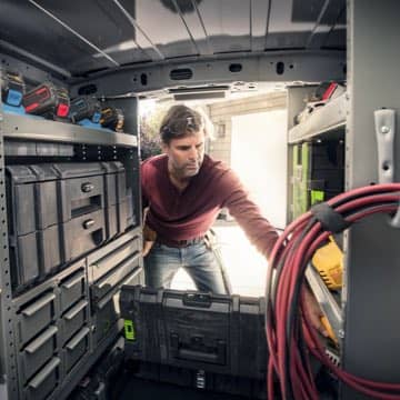 A man retrieving cargo from the back of a Ford Transit Connect Cargo Van
