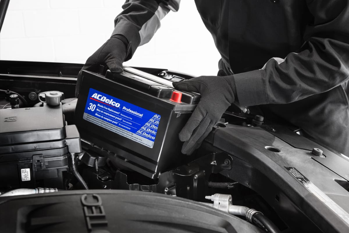 A closeup shot of a service technician's hand replacing a car battery