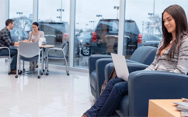 Woman sitting on her laptop in the waiting room of a Chevy dealer in Shreveport