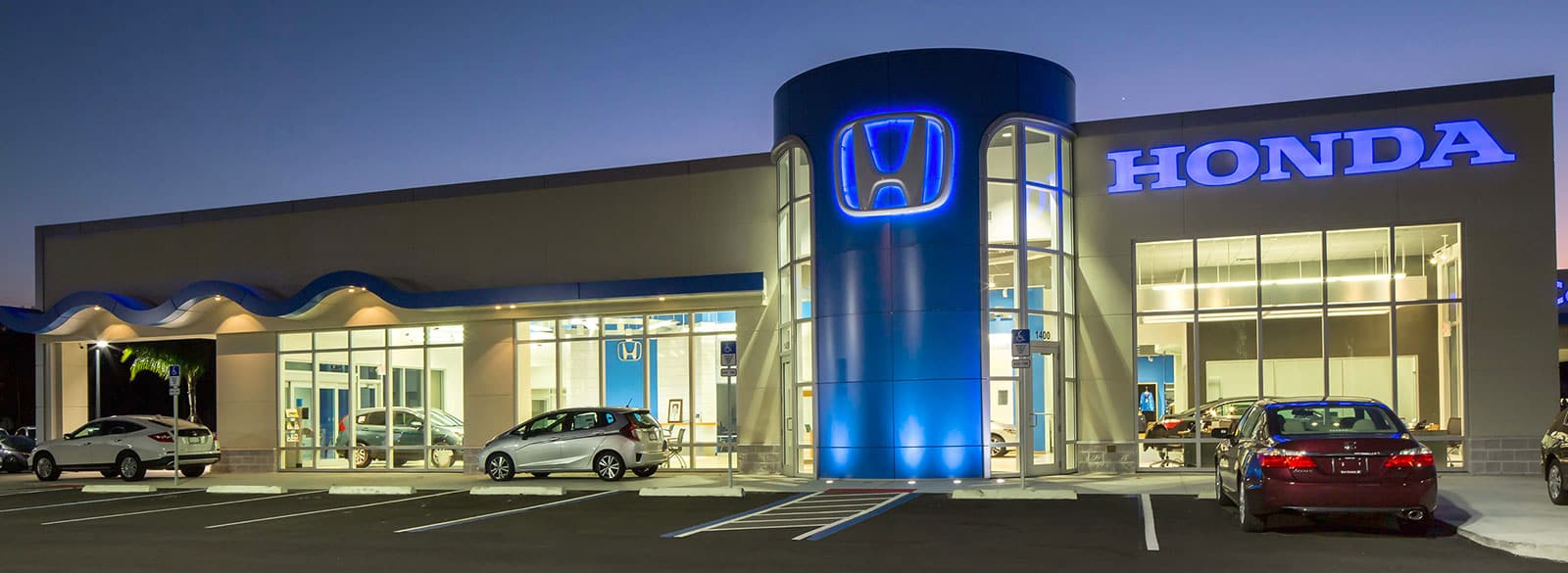 An exterior shot of a Honda dealership at night.