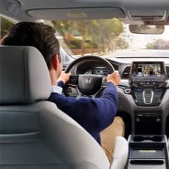 Back View of a Man in a Blue Sweater Driving a Honda Vehicle