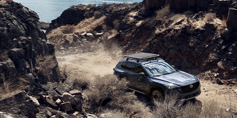 Mazda CX-50 Crossover SUV driving on a dusty mountain road