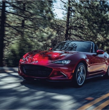 2023 Mazda MX-5 Miata driving on a wooded street
