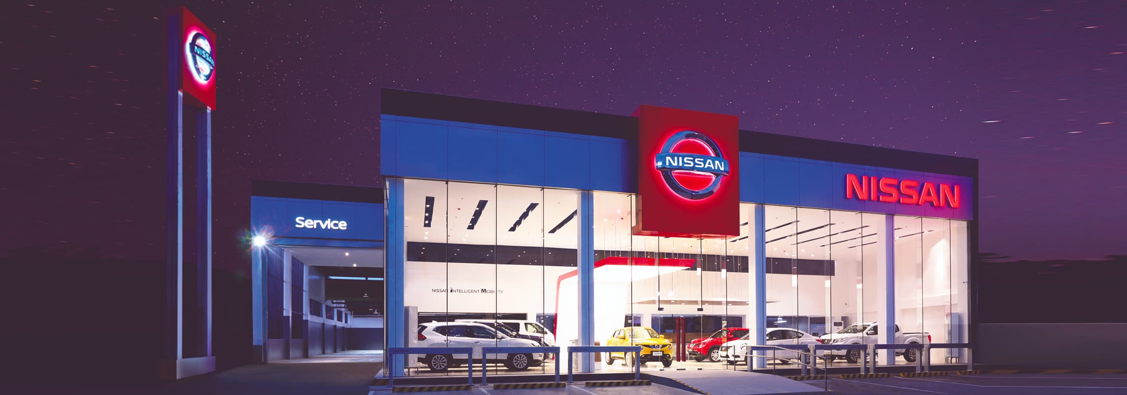 An exterior shot of a Nissan dealership at night