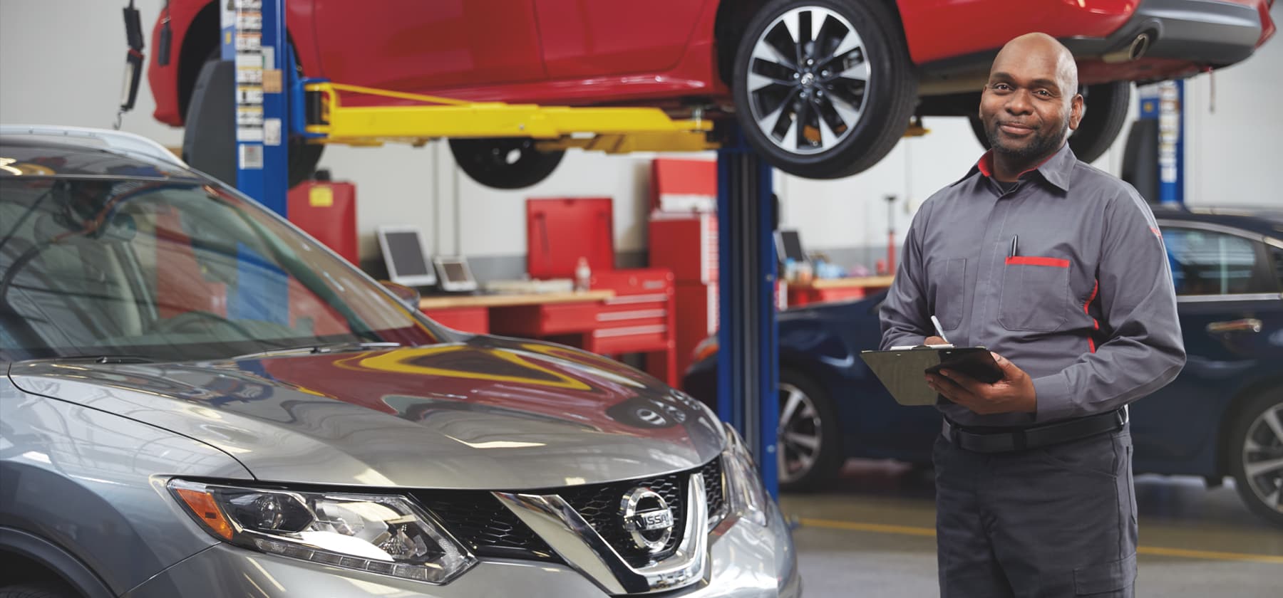 Mechanic standing by silver Nissan SUV