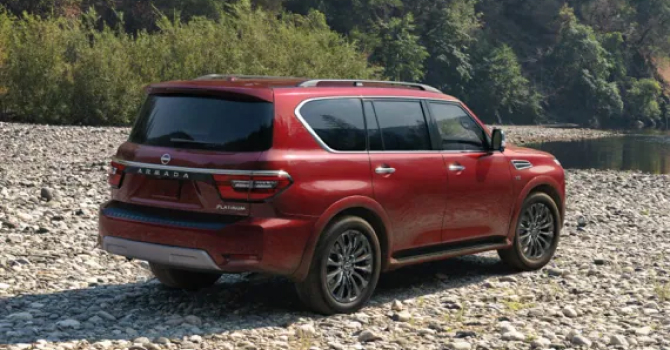 Red Nissan Armada driving over a rocky shoreline